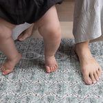 Baby's bare feet on cushioned sage large playmat