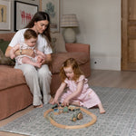 Family sitting together and playing on Totter + Tumble soft spruce play mat in a stylish living room