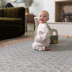 Happy baby playing on a large play mat in a stylish interior setting