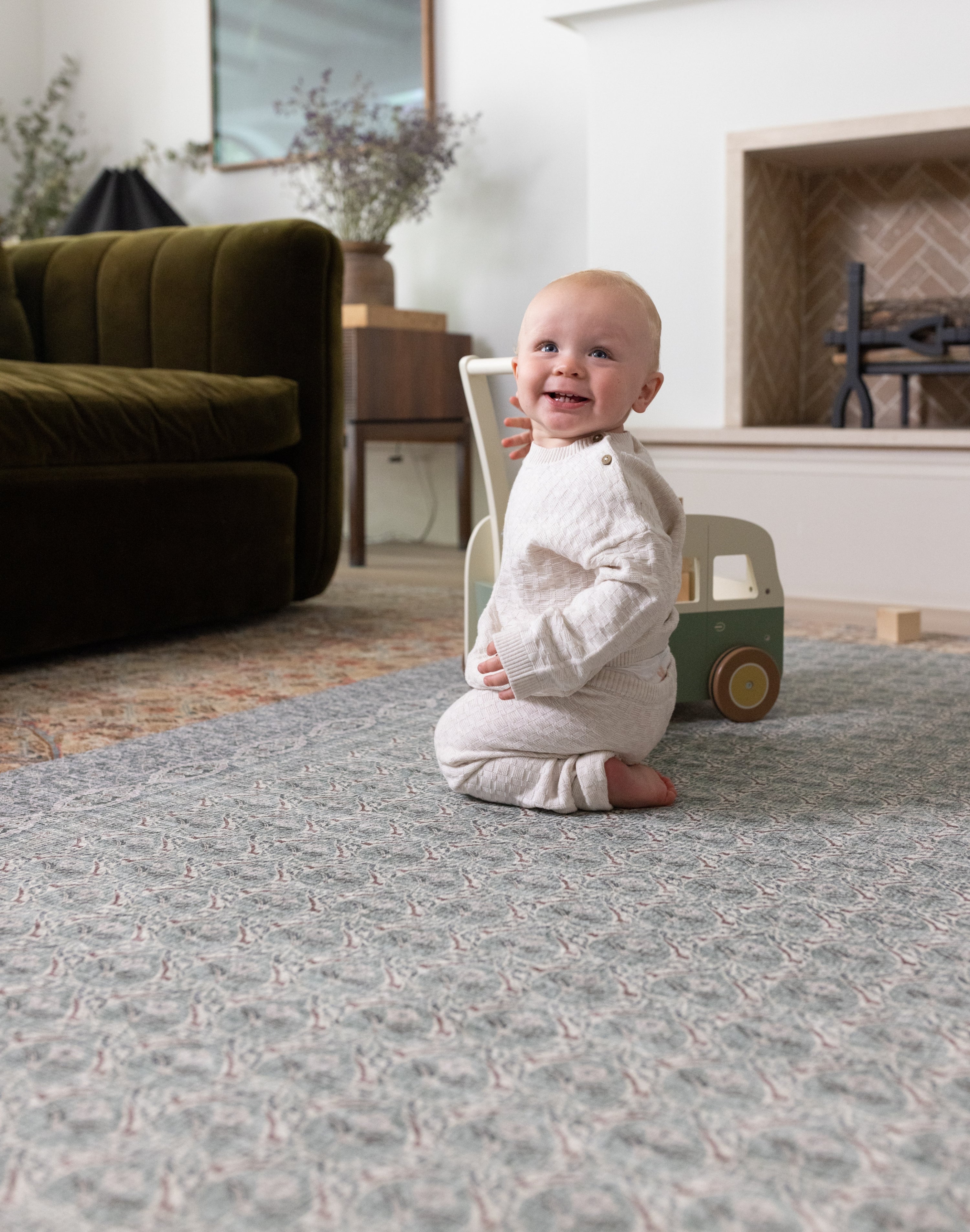 Happy baby playing on a large play mat in a stylish interior setting