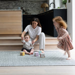 Mum and two children playing  with toys on a thick playmat rug in a modern home