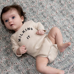 Baby lying happily on patterned green Totter + Tumble baby rug play mat