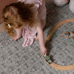 Overhead of a child playing with a toy train set on a patterned baby mat