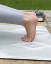 Feet are supported on moulding memory foam exercise mat by Totter & Tumble with textured surface for traction 