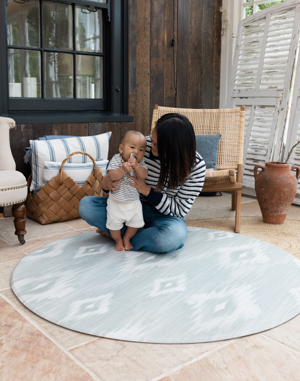 Mom and baby on Round play mat for hard floors by Totter and Tumble so little ones don't feel the floor underneath with stylish green and beige ikat design for a stylish look 