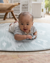 Baby enjoys tummy time on Large round tumble mat by Totter and Tumble with modern ikat design to look like a rug in your home
