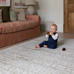 A baby plays on a textured play mat in a dusty pink  family room