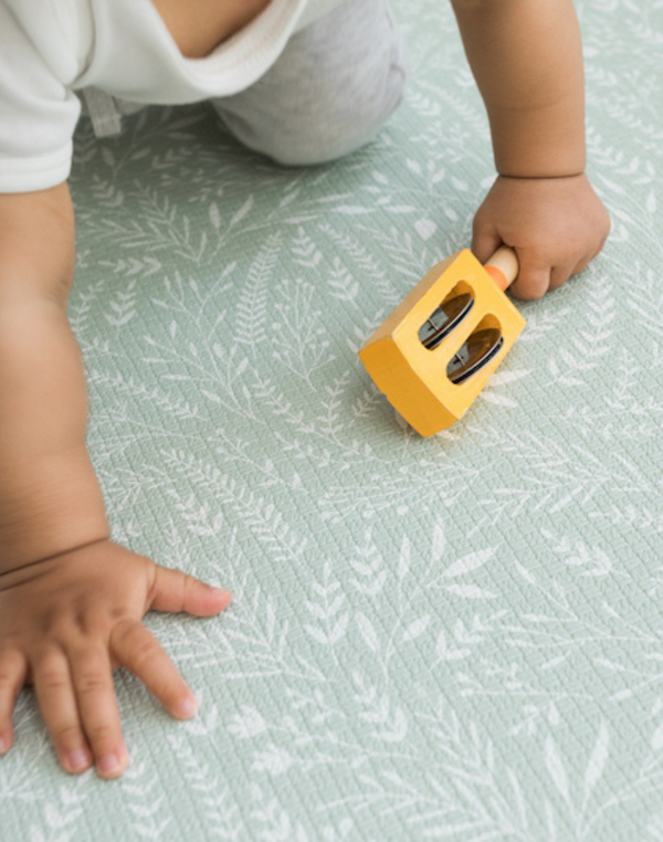 Baby moves across a baby play mat that has a modern botanical design for a stylish look