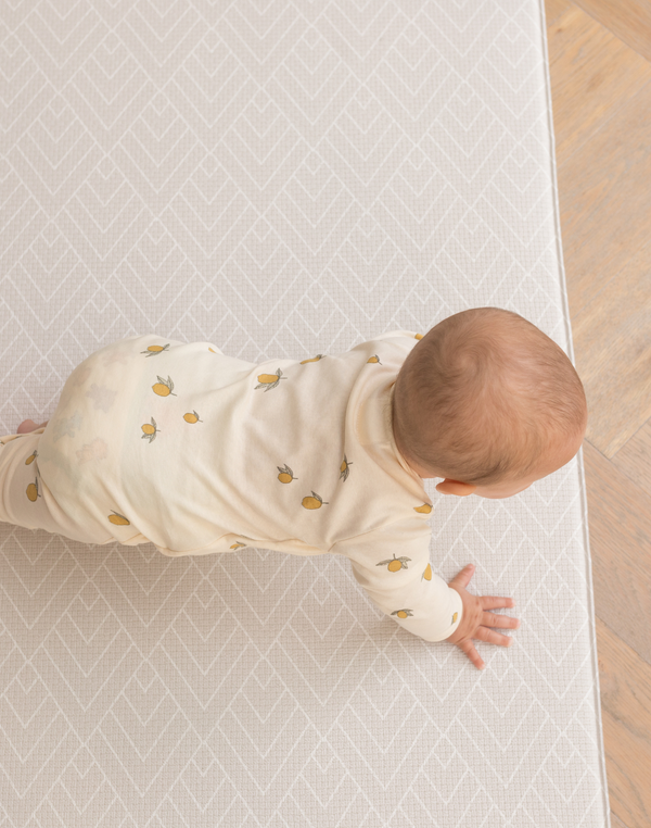 Baby crawls on thick memory foam play mat that makes movement more comfortable on hard wood flooring