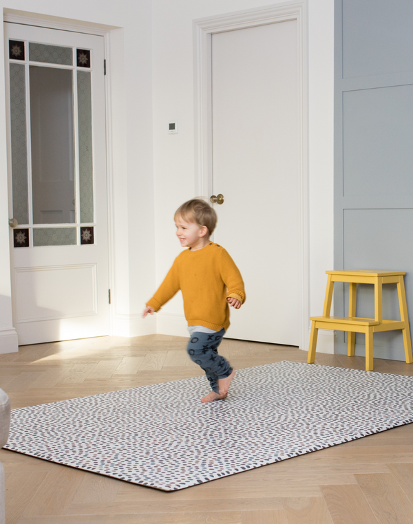 Little boy enjoys play time in the family home with a protective play mat rug
