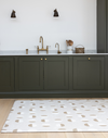Neutral standing mat with a modern solstice design looks stylish against deep green kitchen carpentry