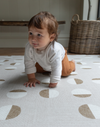 Little baby crawls across a tan play mat with modern motif and non toxic durable design