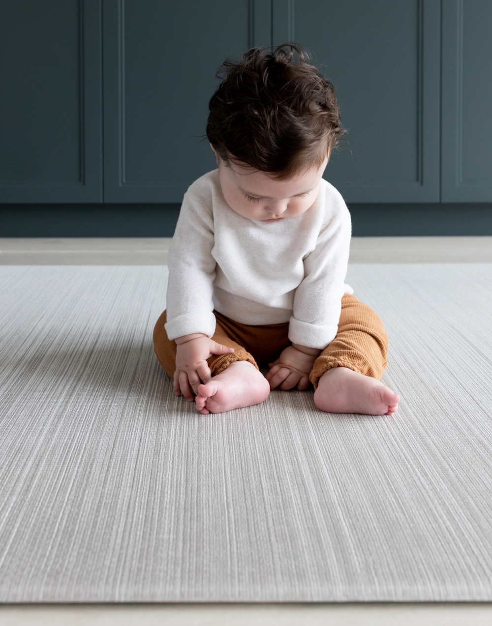Child sitting on the Baby floor mat with stylish beige play mat design for family homes