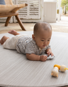 Baby doing tummy time on the round Tumble play mats for added support during floor play The Tali has a tan and beige modern design