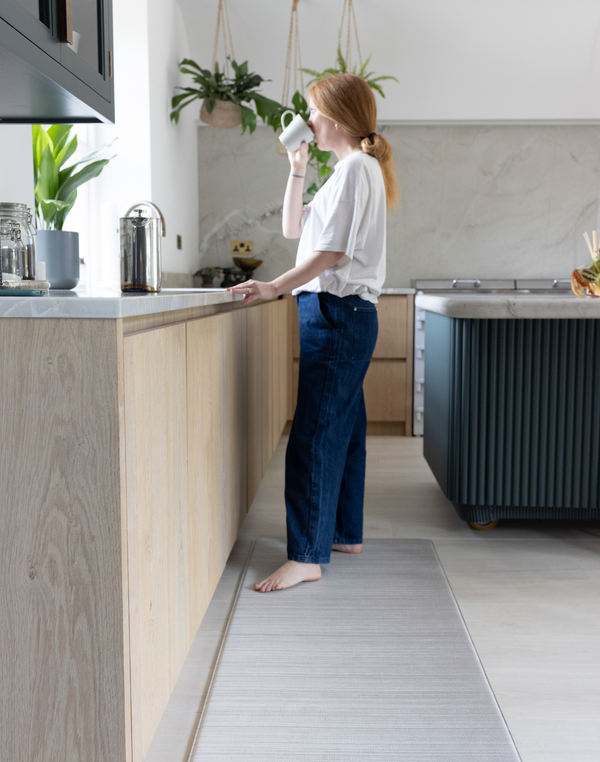 Lady drinking and standing on the Foam runner for support underfoot in the home ideal as a kitchen runner or exercise mat The Tali design has a neutral appeal 