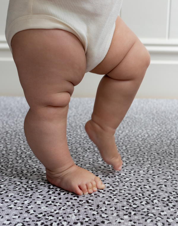 Baby stands on the cushy foam play mat with thick memory foam to asborb shocks and provide comfort