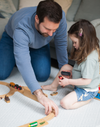 Father and daughter playtime with wooden brio trains on a stylish light grey play rug