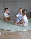 Three babies playing together on round Totter and Tumble play mat with a textured memory foam surface to support little ones as they play featuring the iconic Willow Boughs design from the William Morris archives released for a new generation