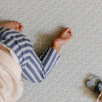 A baby crawling safely and comfortably on the beachcomber shell design play mat from totter and tumble
