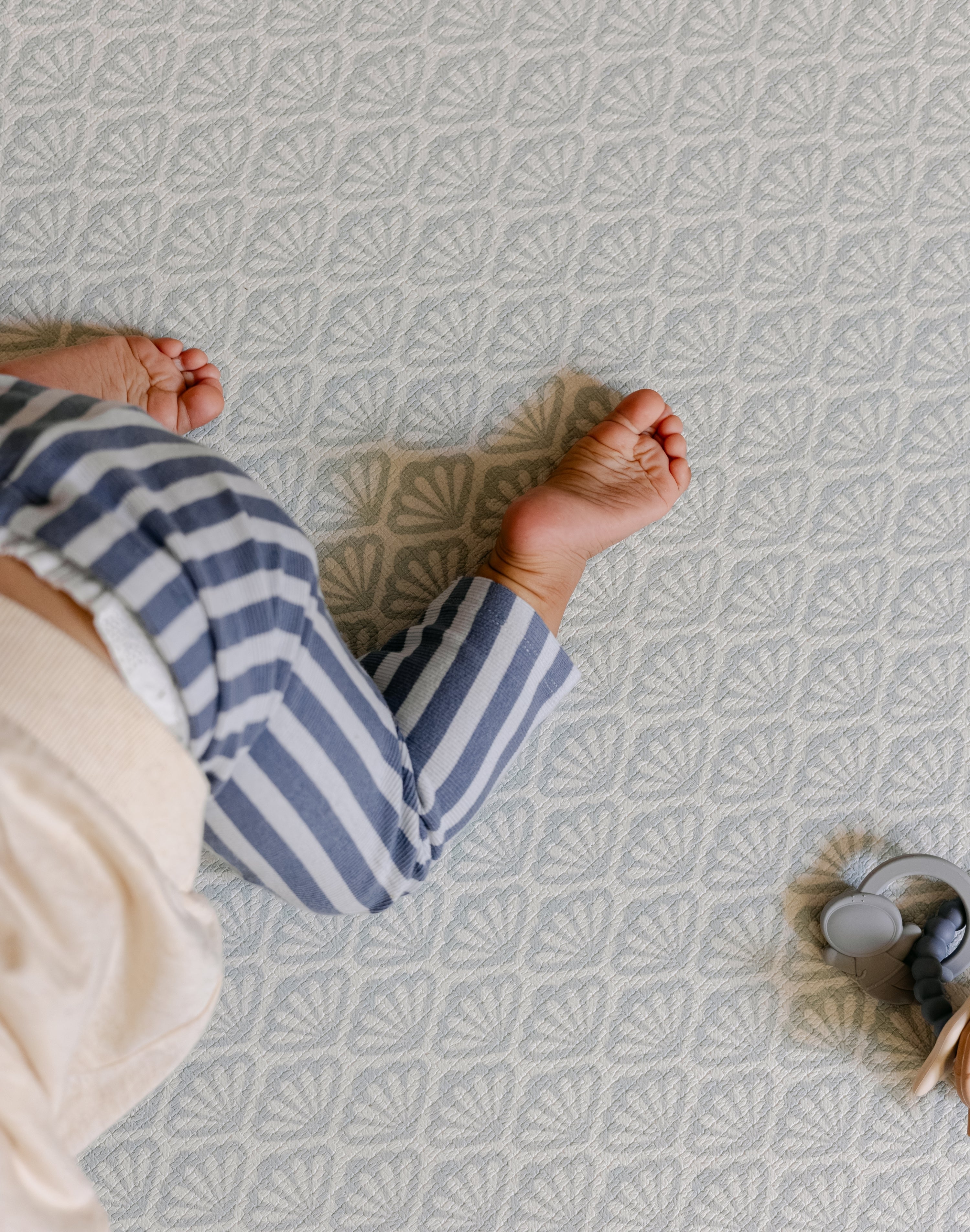 A baby crawling safely and comfortably on the beachcomber shell design play mat from totter and tumble
