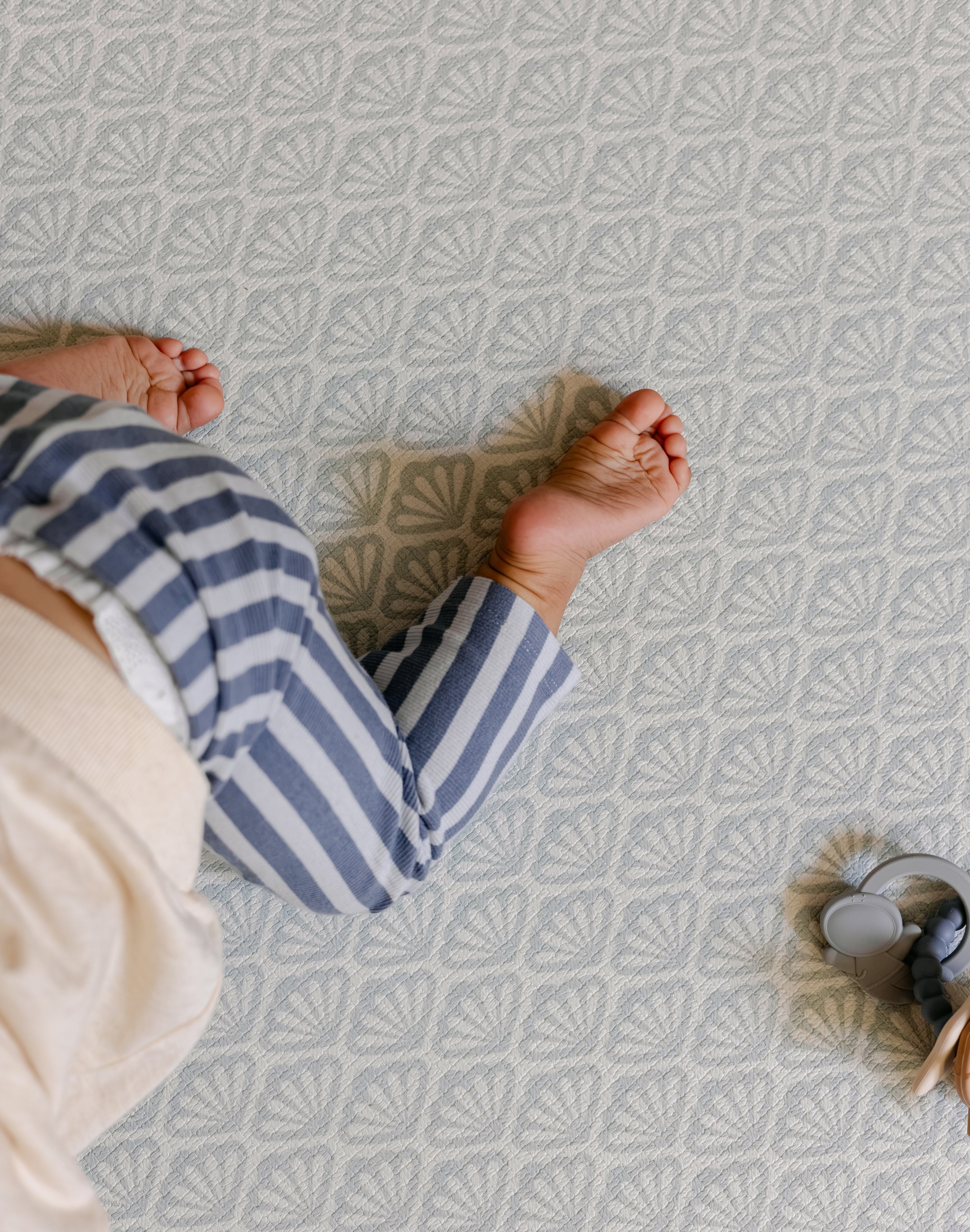 A baby crawling safely and comfortably on the beachcomber shell design play mat from totter and tumble