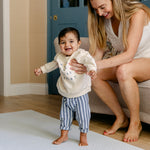 A woman helping a baby stand up safely on The Beachcomber play mat, made from thick safe non toxic memory foam | SKU: 26 BEACH/GATHER XL, 26 BEACH/GATHER STD, 26 BEACH/GATHER COMP