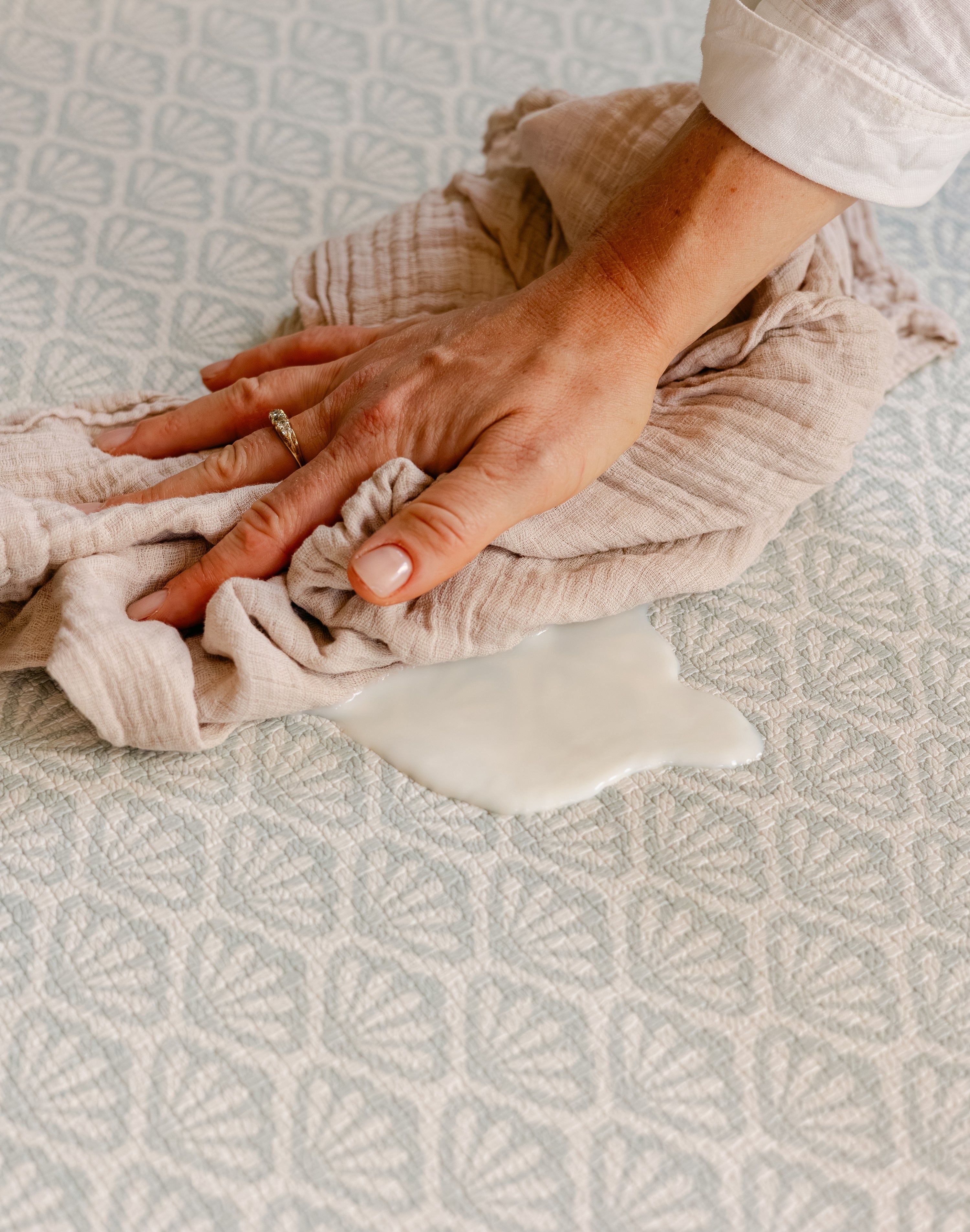Spilt milk being easily cleaned up on The Beachcomber rug-like, soft, safe, memory foam play mat from totter and tumble | SKU: 26 BEACH/GATHER XL, 26 BEACH/GATHER STD, 26 BEACH/GATHER COMP