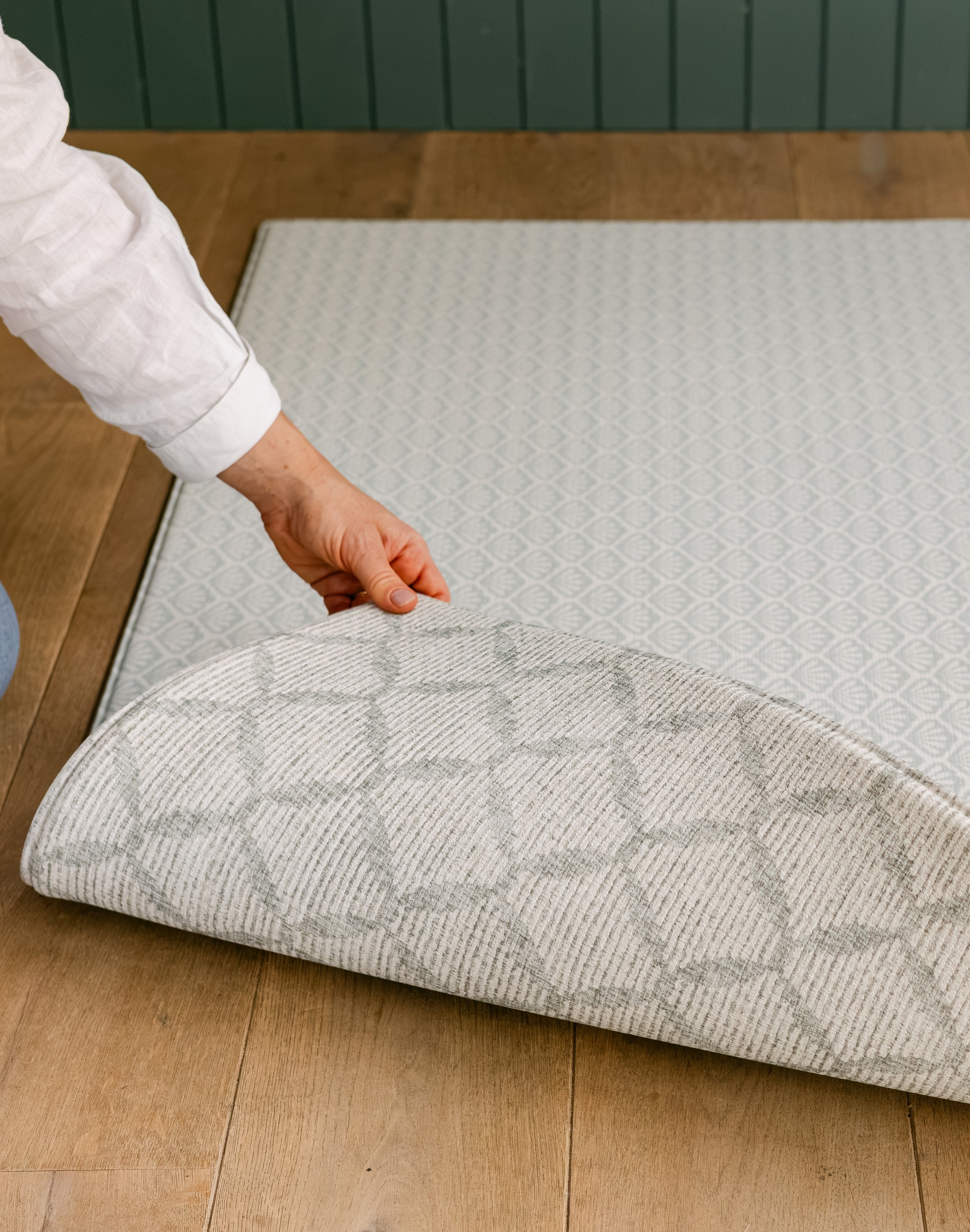 A person showing both sides of the reversible coastal inspired beachcomber play mat | SKU: 26 BEACH/GATHER XL, 26 BEACH/GATHER STD, 26 BEACH/GATHER COMP