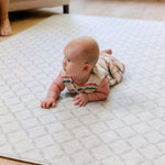 A baby enjoying tummy time on a soft thick non toxic memory foam totter and tumble playmat