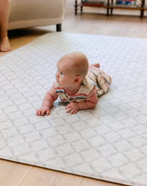 A baby enjoying tummy time on a soft thick non toxic memory foam totter and tumble playmat
