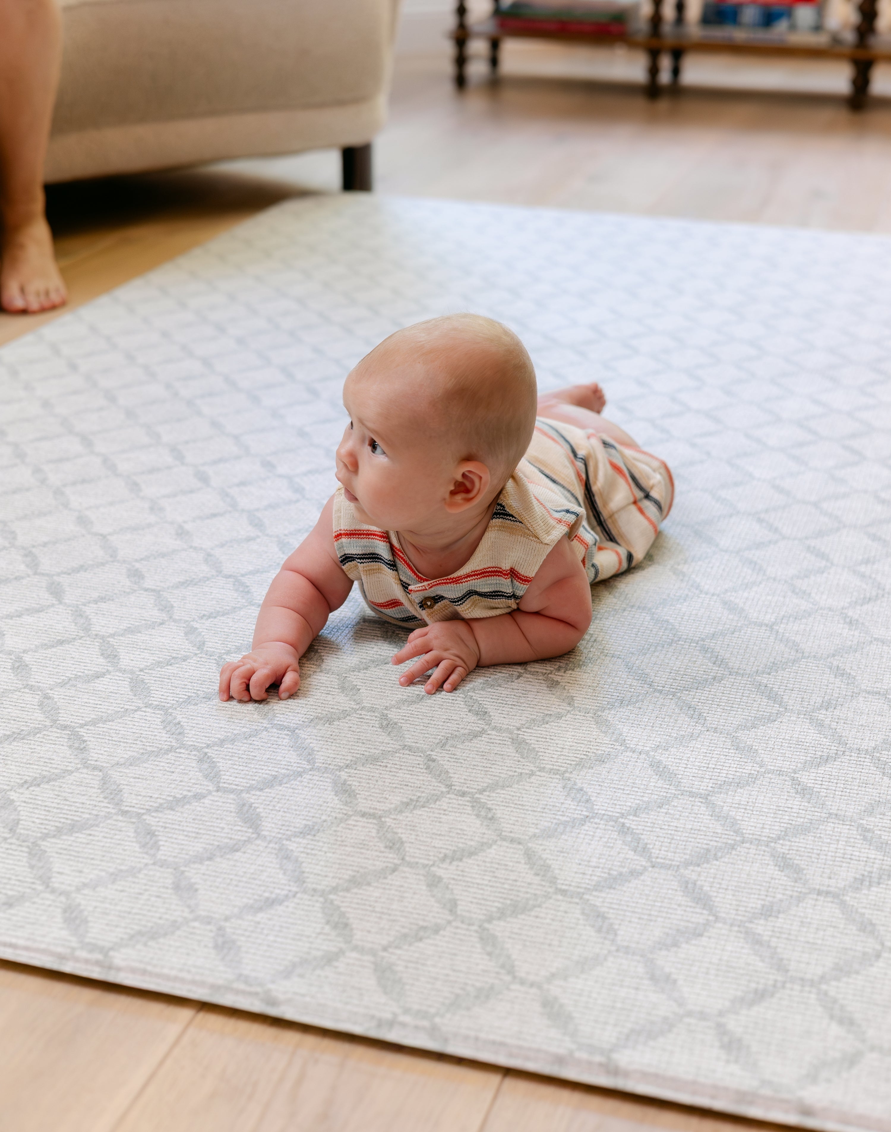 A baby enjoying tummy time on a soft thick non toxic memory foam totter and tumble playmat