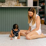 A women sat comfortably with a baby playing on a safe, non toxic, rug-like play mat from totter and tumble | SKU: 26 BEACH/GATHER XL, 26 BEACH/GATHER STD, 26 BEACH/GATHER COMP