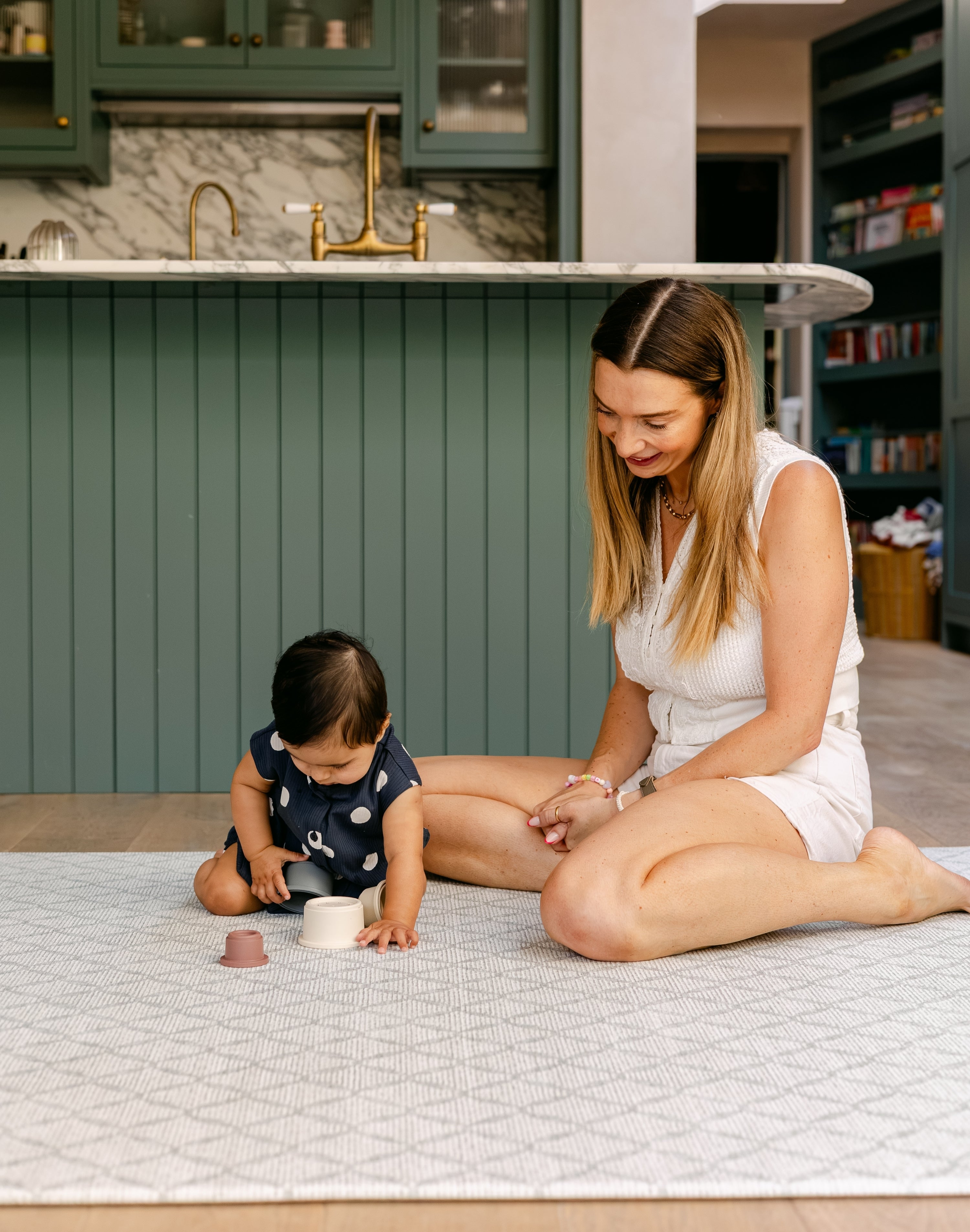 A women sat comfortably with a baby playing on a safe, non toxic, rug-like play mat from totter and tumble | SKU: 26 BEACH/GATHER XL, 26 BEACH/GATHER STD, 26 BEACH/GATHER COMP