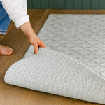 A person showing both sides of the reversible gatherer, coastal inspired design play mat from totter and tumble | SKU: 26 BEACH/GATHER XL, 26 BEACH/GATHER STD, 26 BEACH/GATHER COMP