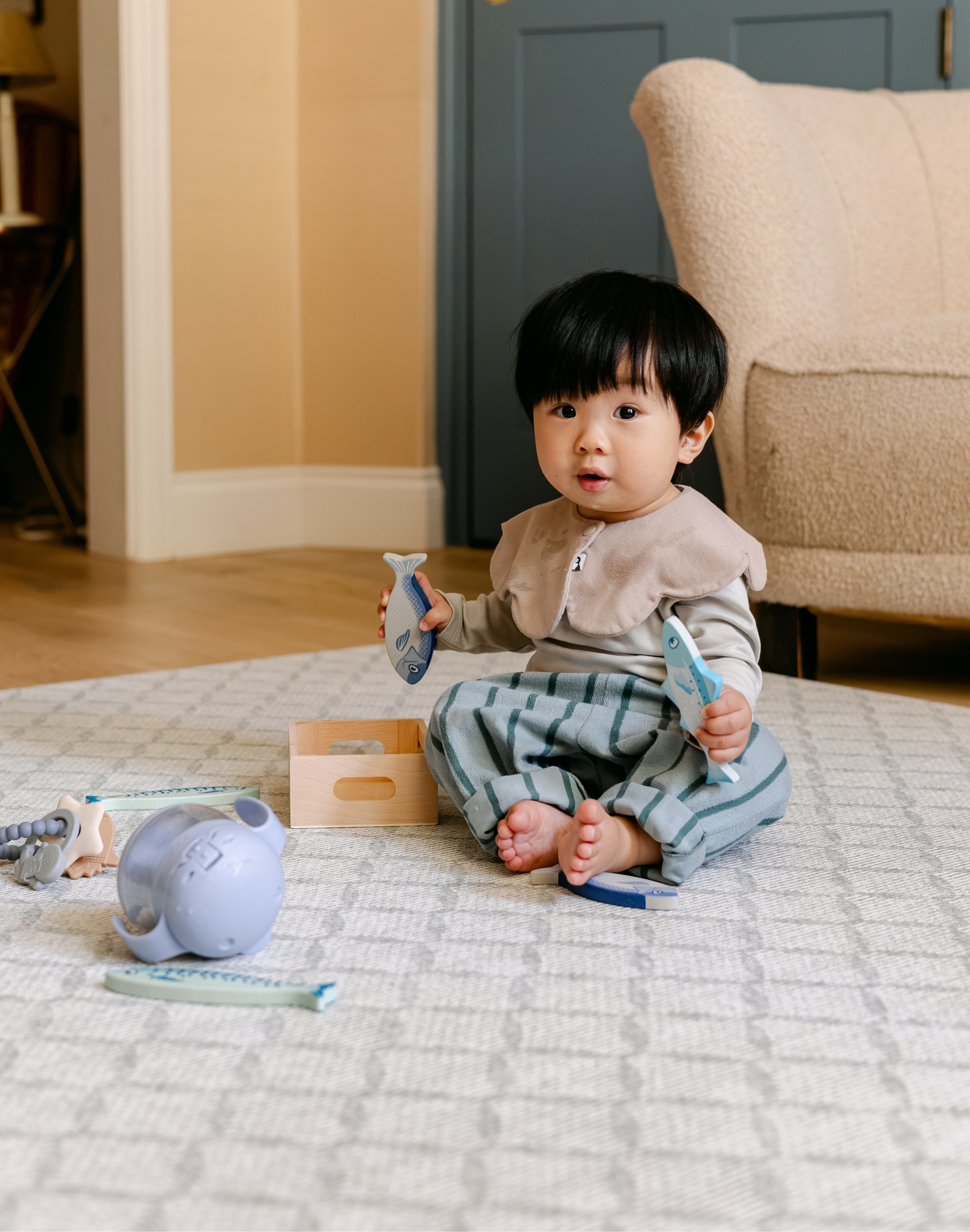 A baby sat comfortably, playing on a rug-like The Gatherer play mat from totter and tumble | SKU: 26 BEACH/GATHER XL, 26 BEACH/GATHER STD, 26 BEACH/GATHER COMP