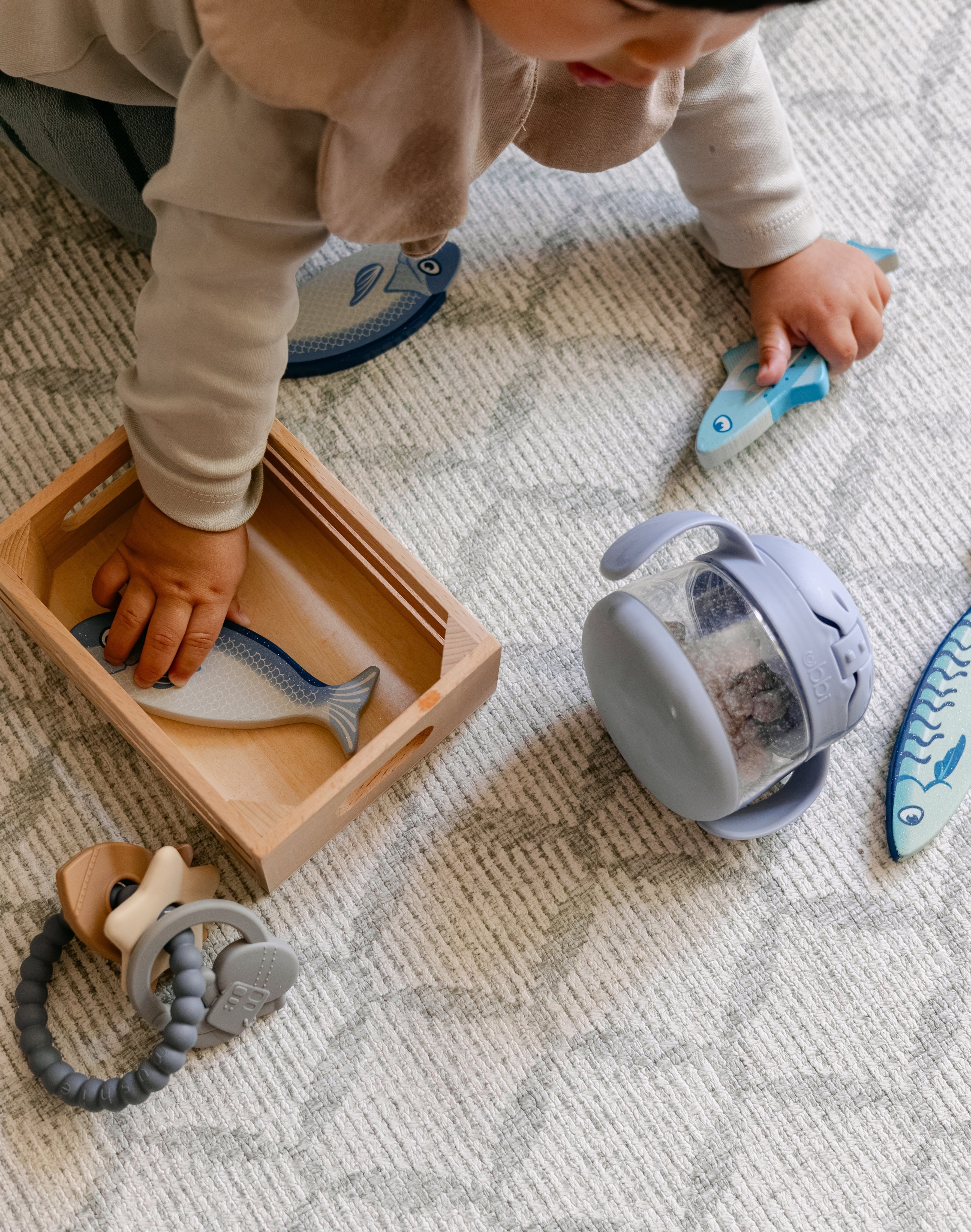 A baby playing with toys on a coastal inspired design play mat, rug-like, soft and safe | SKU: 26 BEACH/GATHER XL, 26 BEACH/GATHER STD, 26 BEACH/GATHER COMP
