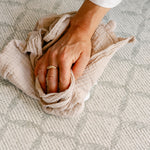 Someones hand easily cleaning up a spill on the thick rug-like totter and tumble the gatherer play mat | SKU: 26 BEACH/GATHER XL, 26 BEACH/GATHER STD, 26 BEACH/GATHER COMP