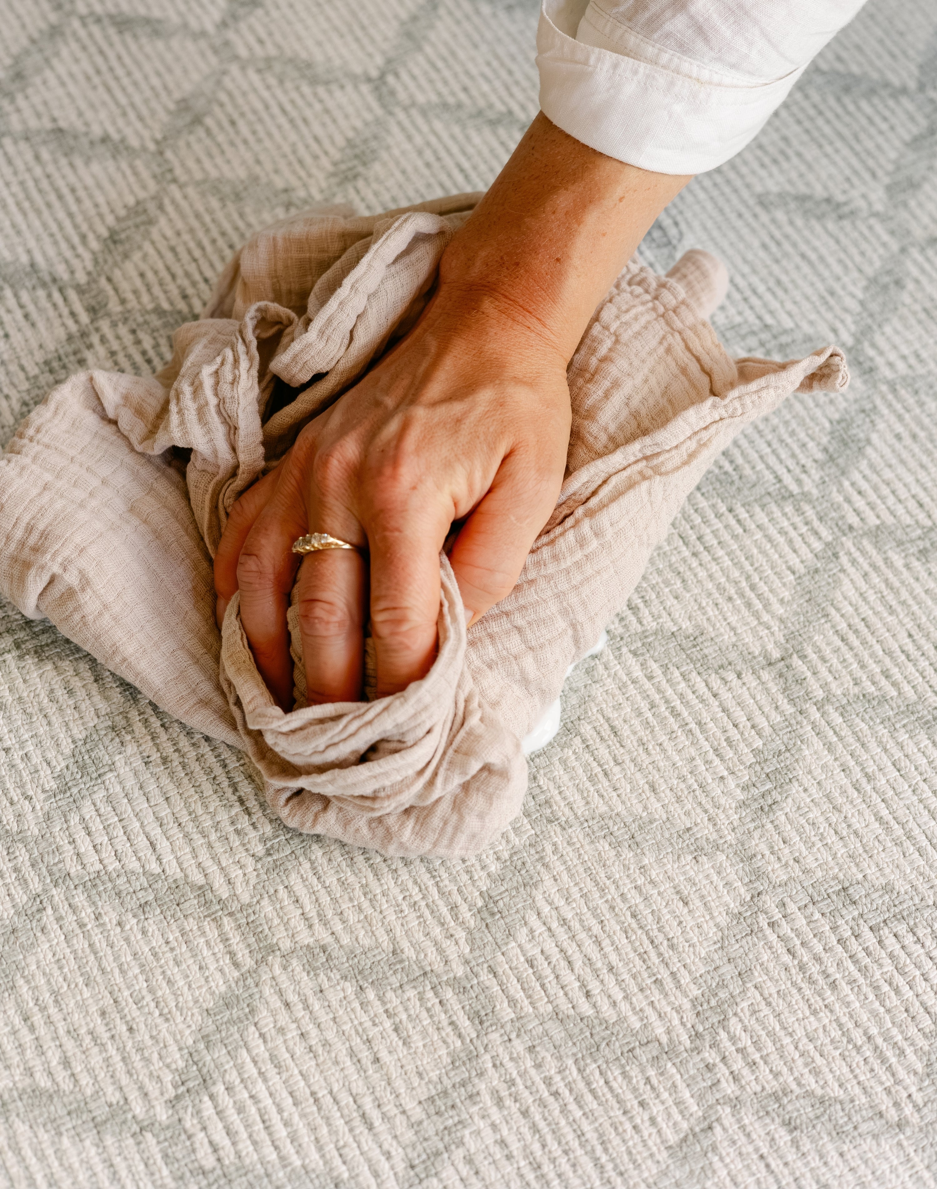 Someones hand easily cleaning up a spill on the thick rug-like totter and tumble the gatherer play mat | SKU: 26 BEACH/GATHER XL, 26 BEACH/GATHER STD, 26 BEACH/GATHER COMP